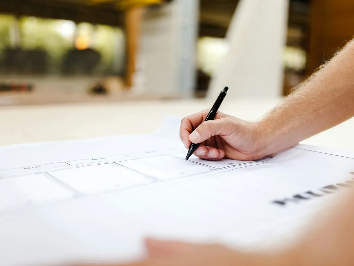 Hand zeichnet mit Stift einen Möbelentwurf auf Papier