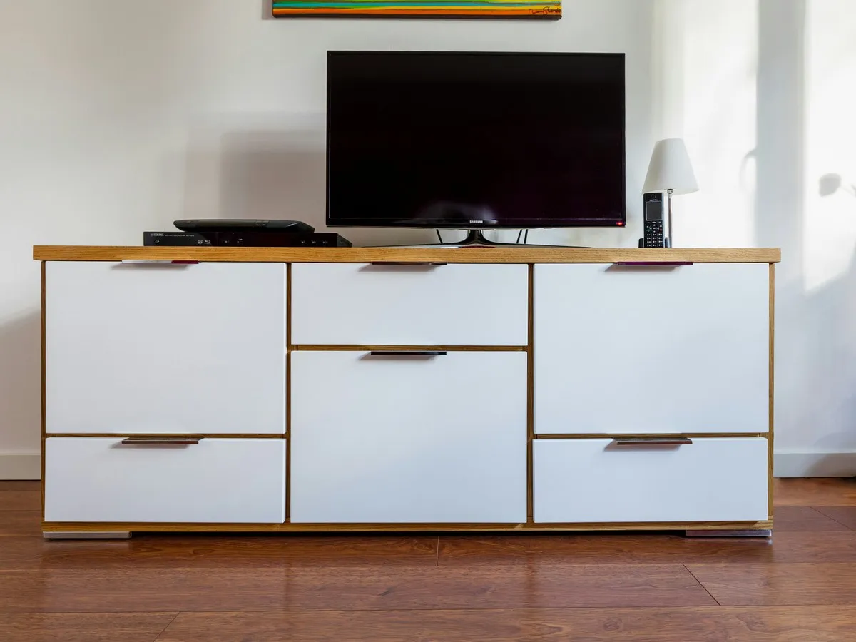 Sideboard mit hellen Fronten und Massivholz-Korpus an einer weißen Wand