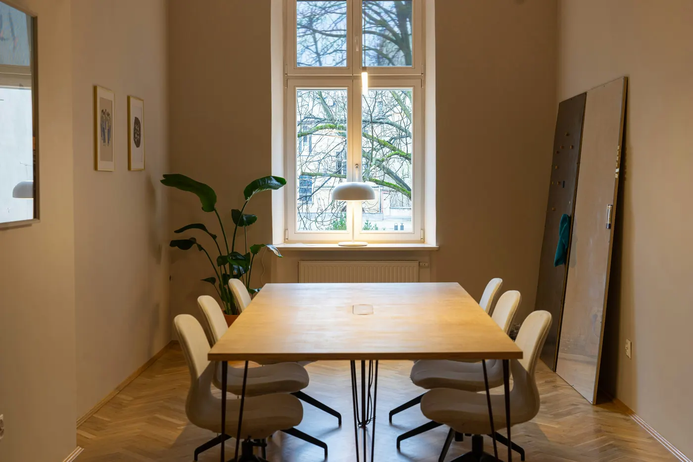 Besprechungsraum mit Holztisch vor einem hohen Altbaufenster