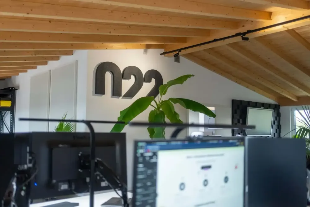 Arbeitsplätze im Büro von 022 unter der Holzdecke, das Logo an der Wand