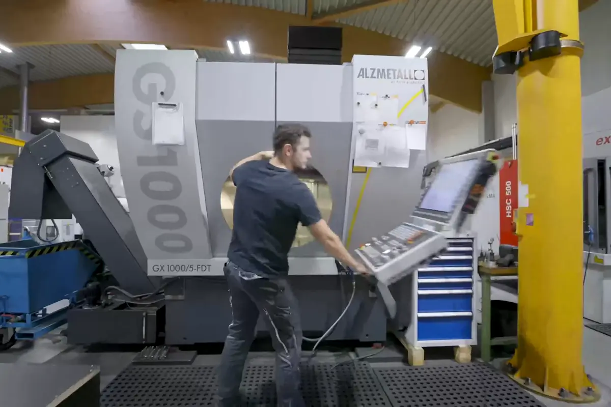 Ein Mitarbeiter an einer CNC-Maschine in einer Produktionshalle, Standbild aus einem Imagefilm von 022